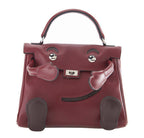 Maroon handbag with heart-shaped clasp on a white background