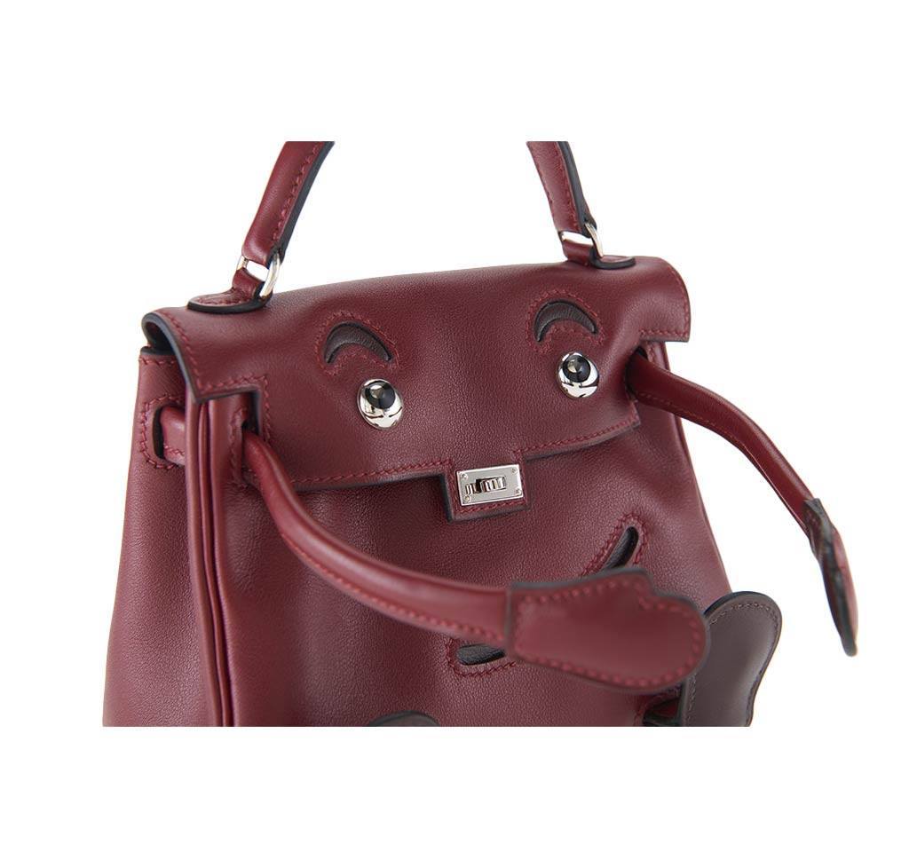Maroon handbag with decorative elements on a white background
