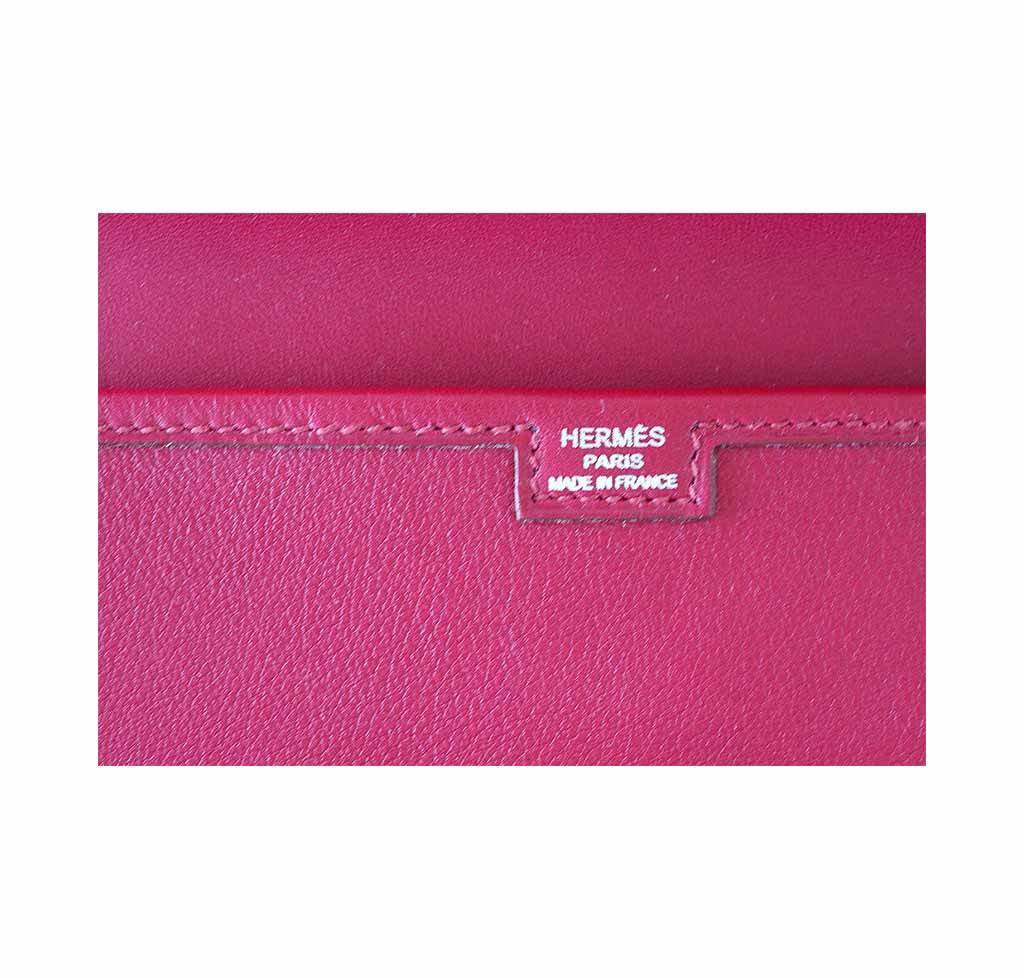Close-up of a pink Hermès wallet with visible branding.
