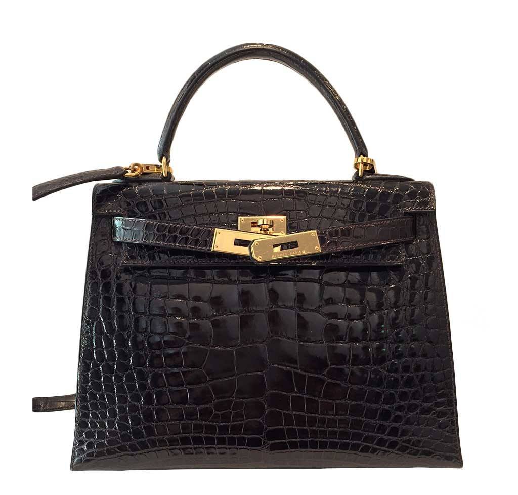 Black crocodile skin handbag with gold hardware on a white background