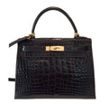 Black crocodile skin handbag with gold hardware on a white background