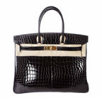 Black crocodile skin handbag with gold hardware on a white background